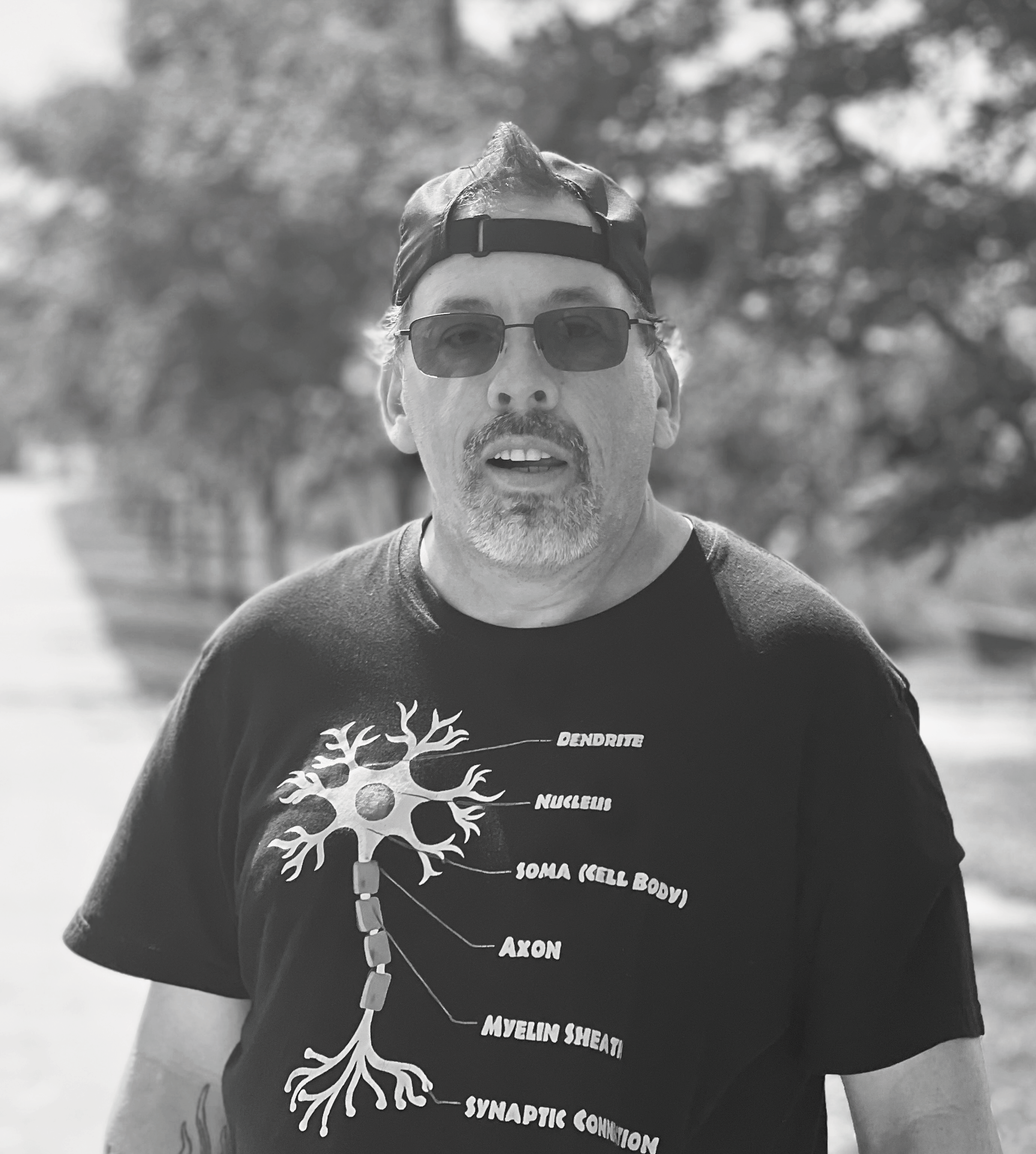 “Black and white outdoor photo of a man wearing a neuron diagram shirt used for CMT website content.”