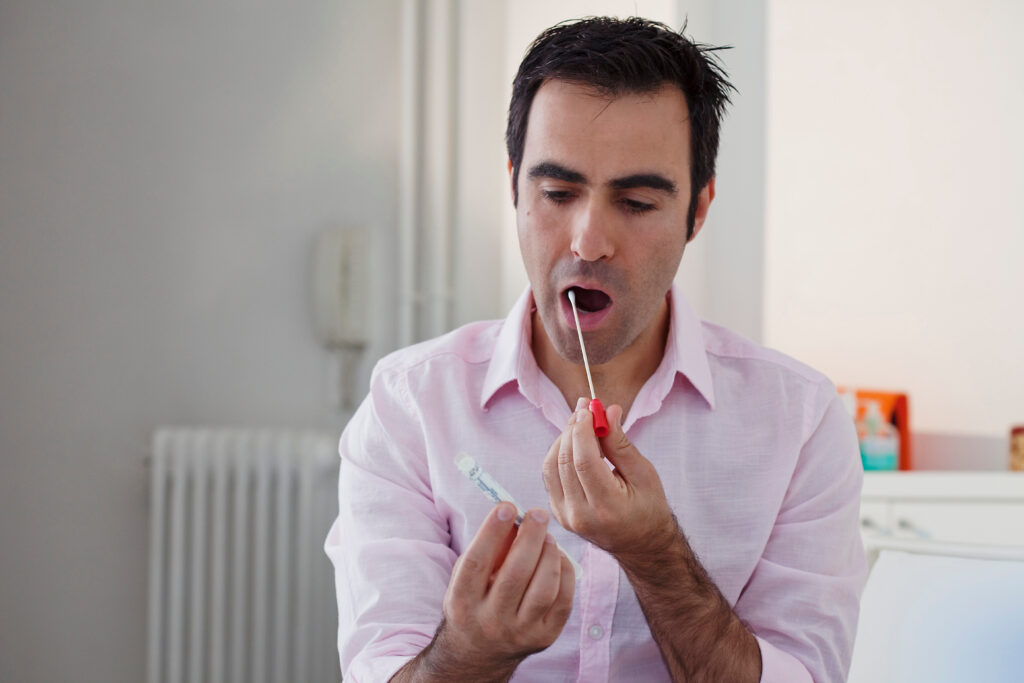 Person holding a saliva collection swab and sample tube while preparing to take an at-home genetic test.